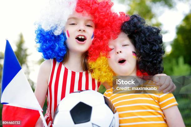 Two Funny Little Sisters Supporting And Cheering Their National Football Teams Stock Photo - Download Image Now