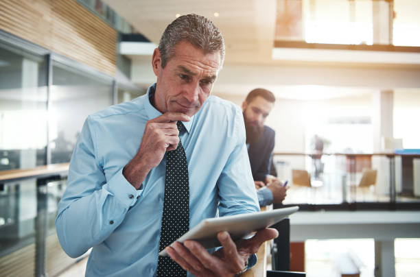 istock Focused mature businessman using a tablet in an office corridor 804477356
