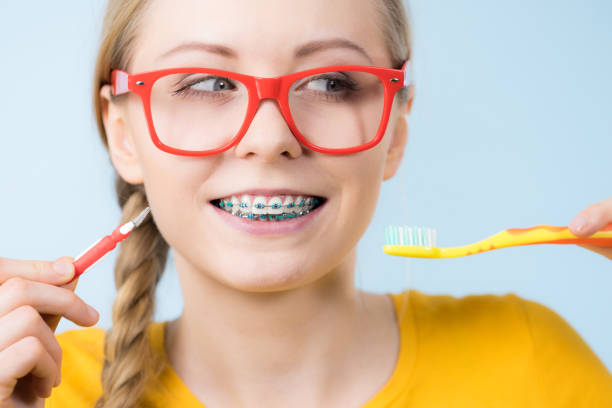 istock Woman smiling cleaning teeth with braces 804490912