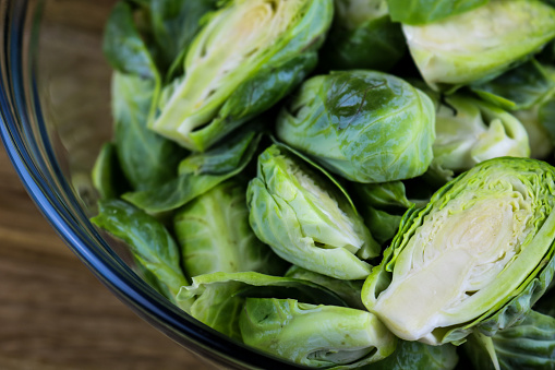 A glass bowl filled with Brussels sprouts cut in half