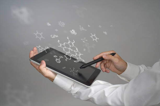Young man scientist with tablet pc and stylus or pen working with chemical formulas on gray background.