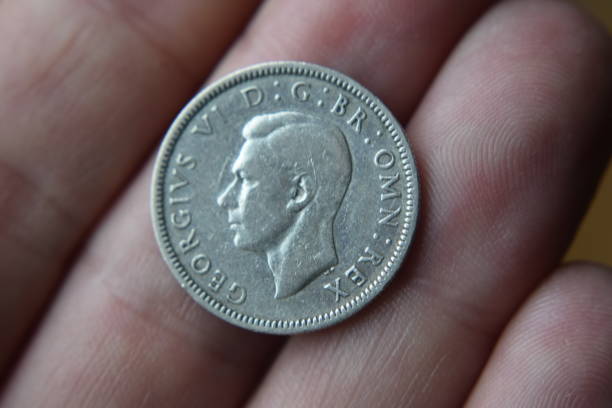 George VI shilling on fingers Image of a George VI silver shilling resting on the fingers of a hand george vi stock pictures, royalty-free photos & images