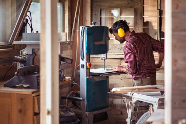 Male Carpenter cutting plank by band saw stock photo