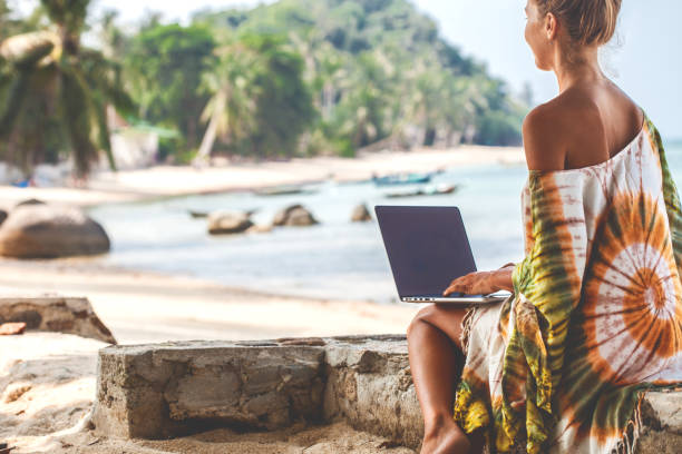 woman at beach working on laptop - on beach laptop working imagens e fotografias de stock