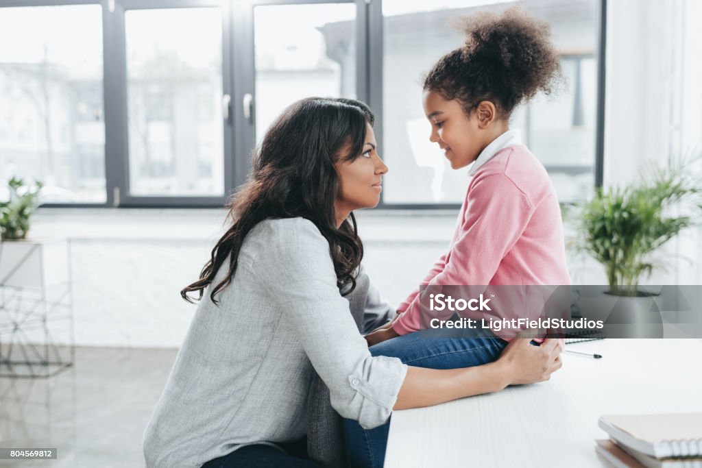 side view of african american mother talking with her daughter indoors Talking Stock Photo