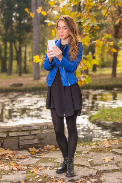 istock Young girl using cellphone in the park with autumn / fall colors. 804569894