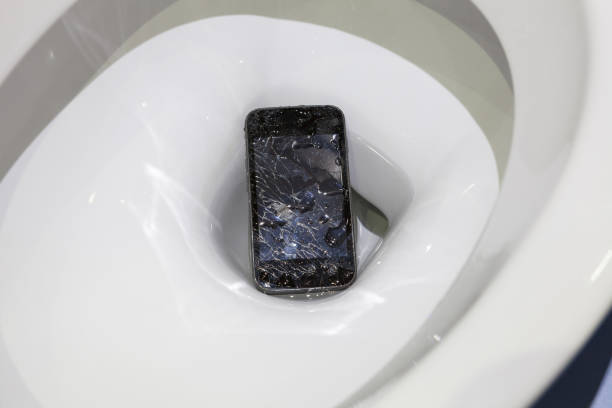 壊れた携帯電話を便器の中に落とした - mobile phone smart phone toilet water ストックフォトと画像