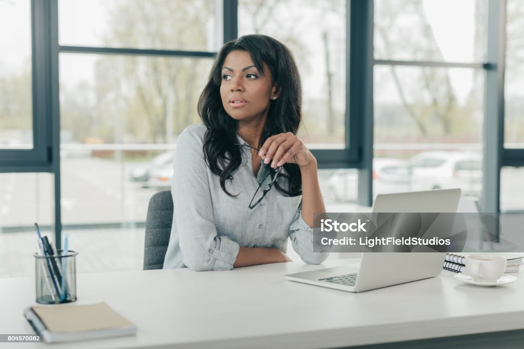 young pensive african american businesswoman sitting at workplace African-American Ethnicity Stock Photo