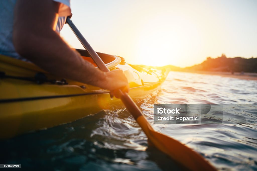 Paddling the kayak Close up of man holding kayak paddle at sunset. Copy space. Kayaking Stock Photo