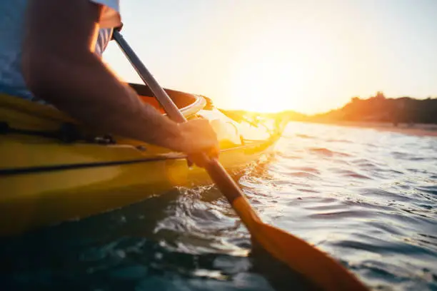 Close up of man holding kayak paddle at sunset. Copy space.
