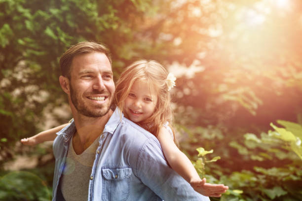 vater tragen tochter huckepack nehmen - family summer portrait nature stock-fotos und bilder