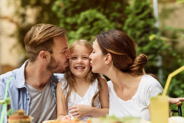 Happy parents kissing a daughter