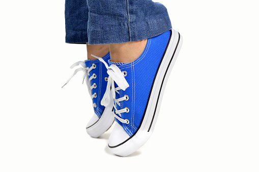 Cropped image of a person wearing sneakers standing on their toes with white background
