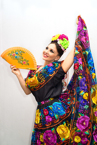 beautiful smiling mexican woman in traditional mexican dress with fan