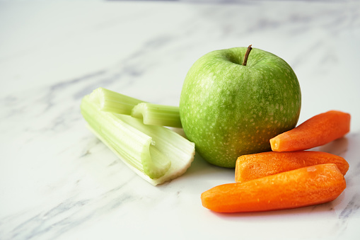 green apple, carrots and celery on marble background