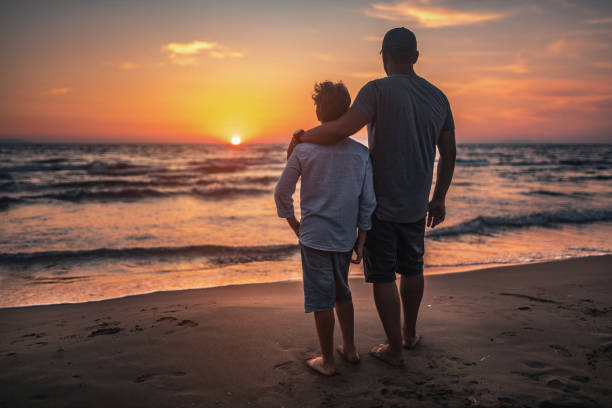 Father and his son watching sunset at sea