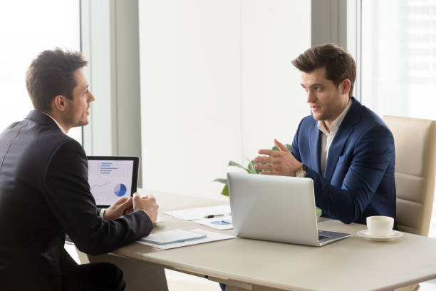 istock Serious businessmen in office discussing project, analyzing charts on laptops 804671334