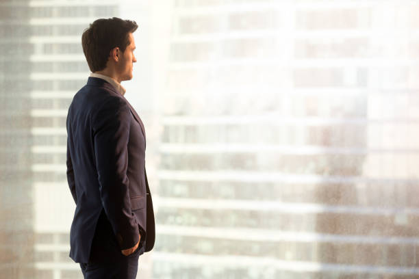 istock Thoughtful successful businessman looking at city standing in office, copyspace 804671632