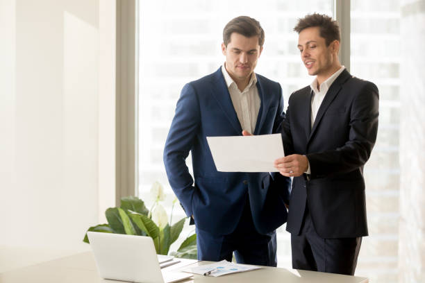 istock Two smiling businessmen talking about eligible investment, discussing presenting document 804671750