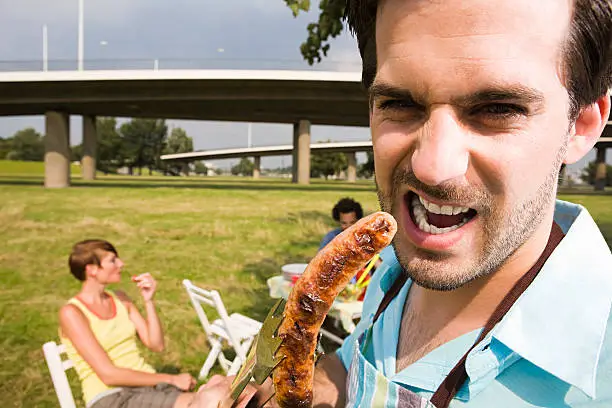 Photo of Man eating a barbecued sausage
