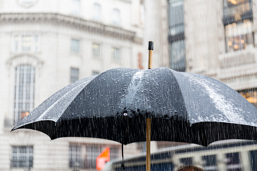Large black umbrella under rain in Regent Street London