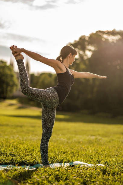 istock Young attractive woman doing dancers yoga pose outdoors on field 804777730