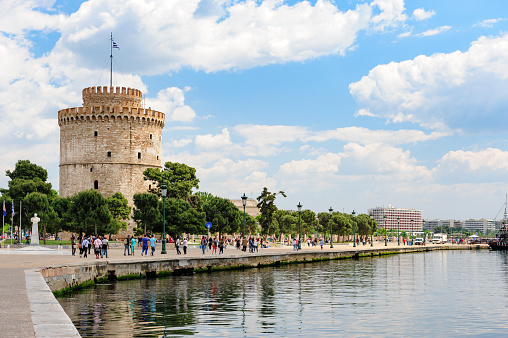 Thesalloniki, Macedonia, Greece - 12th May 2015: People walking and relaxing near white Tower, Thessaloniki, Greece. This tower is a monument and museum on the waterfront of the city.