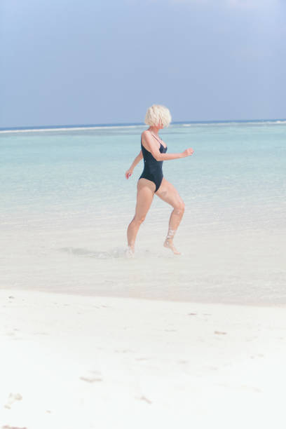 istock Woman in bikini running through water on sandy beach, Maldives 804827394