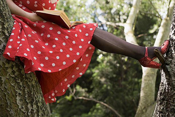 frau liest ein buch auf einem baum - book reading dress women stock-fotos und bilder