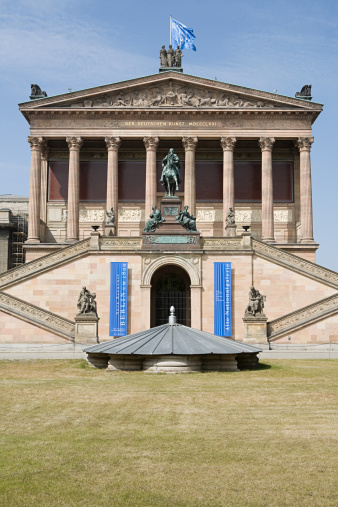 Old darkened facade of the church with columns, arches, sculptures and decor. Protestant Cathedral. Ancient architecture. Germany, Berlin, August 2022.