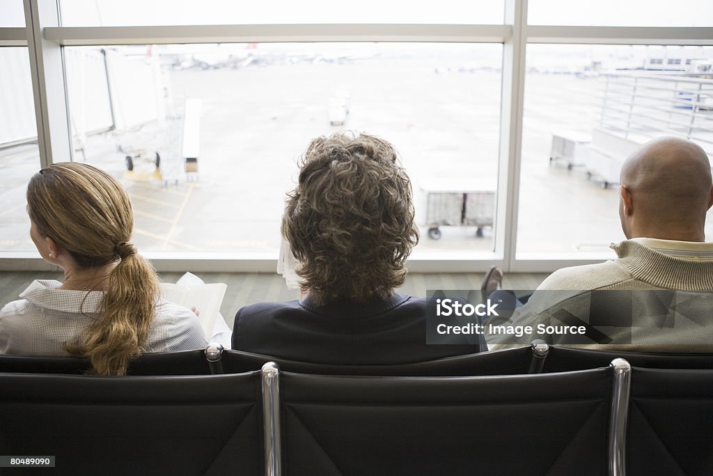 Trois personnes d'attente dans le terminal de l'aéroport - Photo de Salle d'embarquement libre de droits