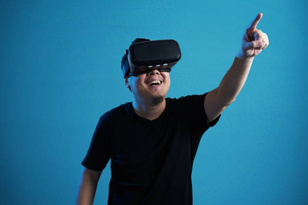 istock Asian man wearing virtual reality goggle and pointing up . 804914402