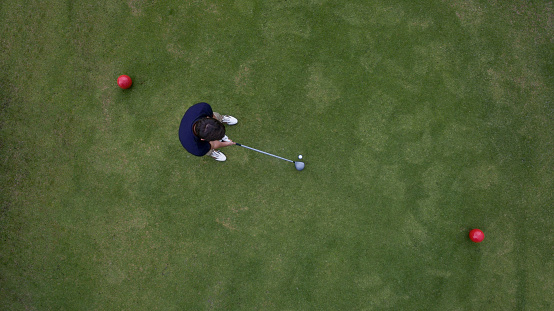Aerial view of man playing golf and standing on the tee box ready to hit the ball - sports training concepts