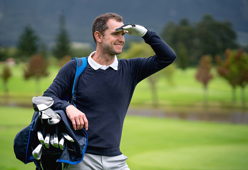Portrait of a man playing golf and looking away at the course - outdoors sports concepts