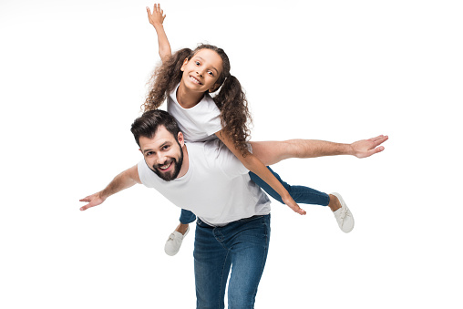 father and daughter piggybacking and looking at camera isolated on white