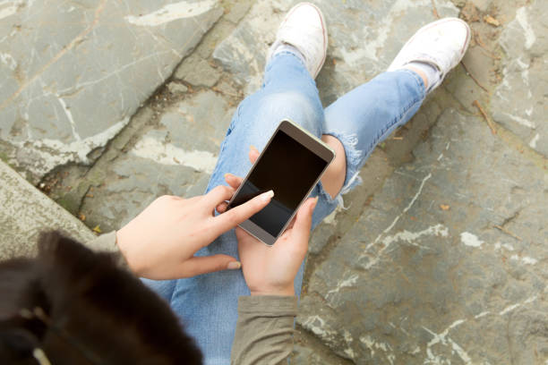 istock Girl texting while sitting on the stairs outdoors. 804964880