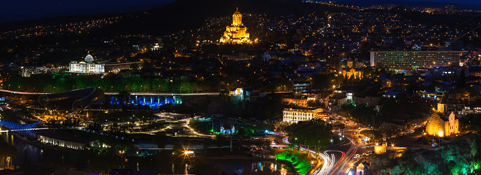 Night panorama view of Tbilisi, capital of Georgia country. Metekhi church, Holy Trinity Cathedral (Sameba) and Presidential Administration at night with illumination and moving cars.