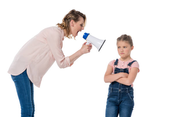 madre enojada con megáfono gritando a la niña de pie con los brazos cruzados - relationship difficulties audio fotografías e imágenes de stock
