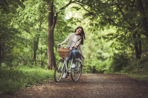 Happy woman having fun while riding a bicycle through the forest.