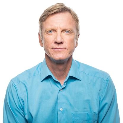 Portrait of serious mid adult man in blue shirt looking at camera on white background.