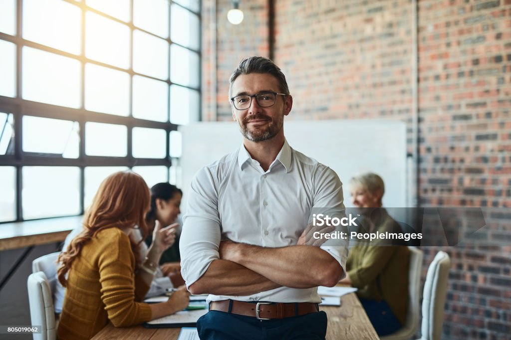 Nothing can break our team Cropped shot of a businessman standing in the office with his arms folded looking confident and smiling at the camera Businessman Stock Photo