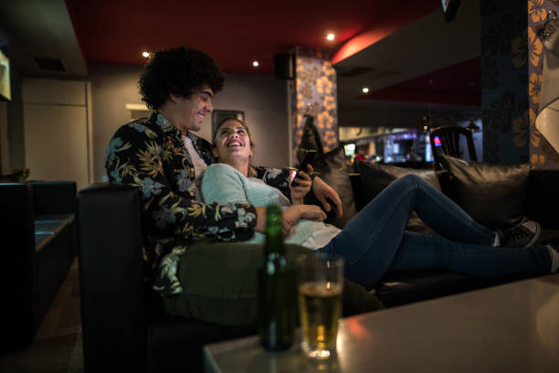 Happy couple talking to each other while spending their time in a cafe. Woman is using mobile phone.