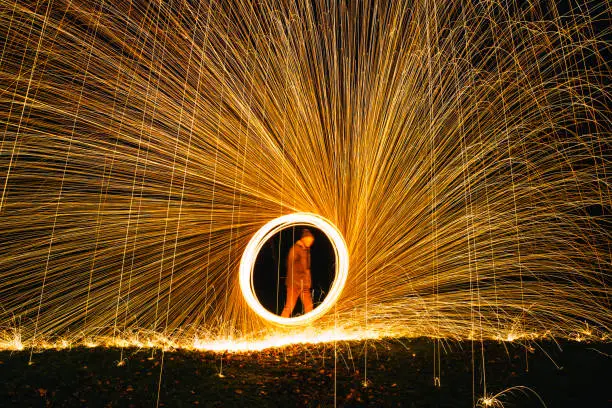 Mature male spinning lit wire wool to create a fan effect.