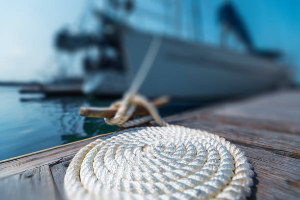 Perfectly coiled rope Perfectly coiled rope on the pier with secured yachts on the background mooring line stock pictures, royalty-free photos & images