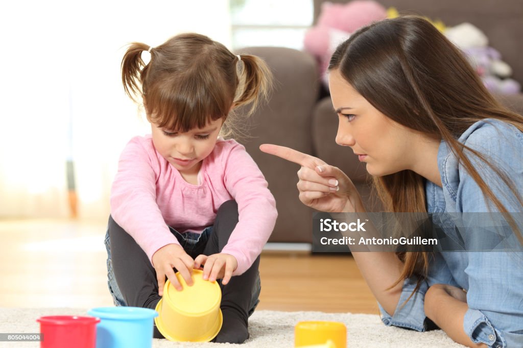 Mother scolding to her baby daughter Portrait of a mother scolding to her baby daughter sitting on the floor in the living room at home Scolding Stock Photo