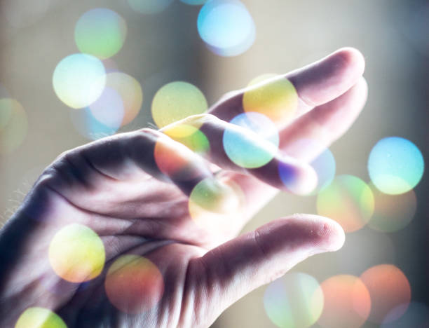 istock Hand Reaching Up through Pastel Yellow Color Bokeh 805050438