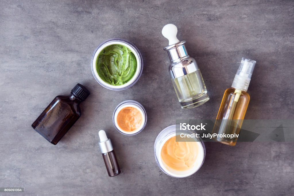 Bottles and jars with natural cosmetics Bottles and jars with natural skincare cosmetics, creams and oils on dark background. Plant-based beauty products. Top view Merchandise Stock Photo