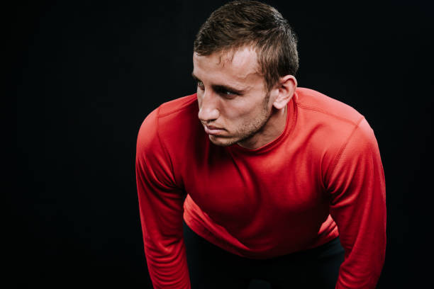 istock Handsome muscular athlete taking break standing against dark background. Tired young Caucasian runner resting after hard training. Fitness and healthy lifestyle concept. 805059070