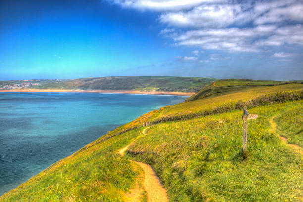 Coast path sign to Woolacombe Devon England UK in summer with blue sky Coast path sign to Woolacombe Devon England UK in summer with blue sky in colourful hdr croyde photos stock pictures, royalty-free photos & images