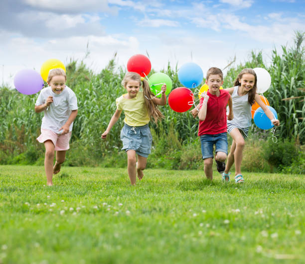 istock Four happy kids running on green lawn 805069448
